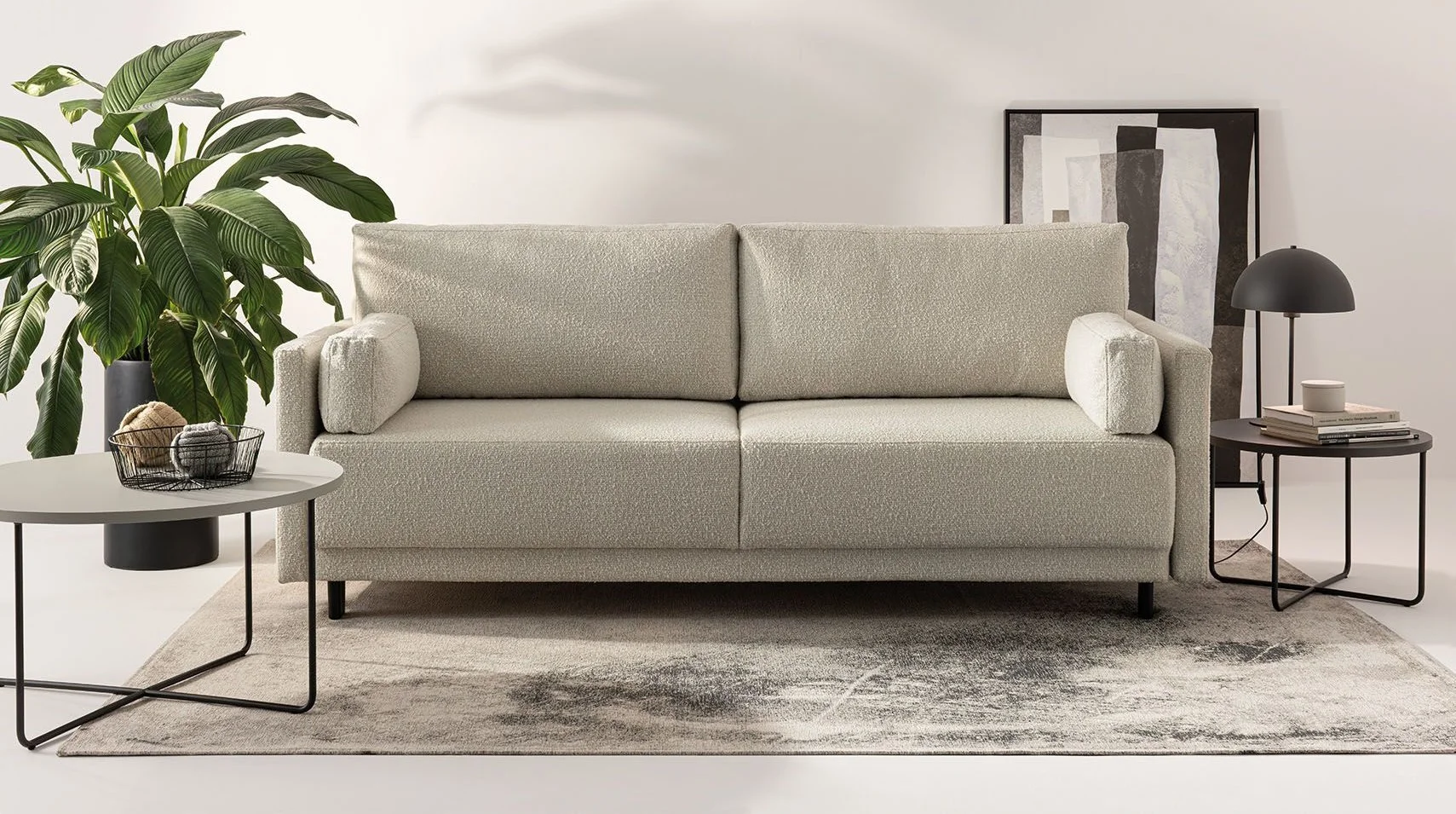 Sofa z tkaniny boucle na dekoracyjnym dywanie z subtelnym wzorem.